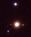 Autor: Petr Škoda - Jeden z nalezených objektů. Složité emisní spektrum je vyzařováno z trojice červených hvězd uprostřed obrázku. Snímek je z archivu projektu PanSTARRS.