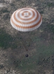 Návratový modul Sojuzu se snáší na padáku do stepi