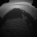 Snímek z levé přední kamery pod palubní deskou v plném rozlišení ukazuje tmavé velké duny a především vysokánský kopec Mount Sharp. NASA/JPL-Caltech