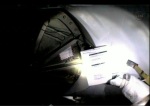 Chris Cassidy uvnitř přechodové komory drží v ruce tahák s procedurami dekontaminace skafandrů a natlakování komory Autor: TV NASA
