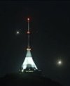 Autor: Martin Gembec - Jupiter s měsíčky (zleva Callisto, Io a Ganymed) a jasná Venuše vpravo od vysílače a hotelu na Ještědu 12. 8. 2025. Dalekohled WO FLT98 a kamera ASI294MC Pro v ohnisku 512 mm (screenshot ze streamu na Youtube / iQLANDIA)