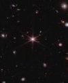 Autor: NASA, ESA, CSA, STScI - Kvasar J0100+2802 vypadá v detailu jako červená hvězda s difrakčními kříži. Ve skutečnosti jde o extrémně vzdálenou supermasivní černou díru, jádro aktivní galaxie.