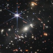 Na prvním snímku JWST nám byl odhalen velmi malý kus oblohy, kde se skrývá nepřeberné množství vzdálených galaxií. A gravitace kupy těch bližších nám zobrazuje zesílené obrazy mnohem vzdálenějších galaxií za ní. Hvězd, které vznikly krátce po velkém třesku. Autor: NASA/ESA