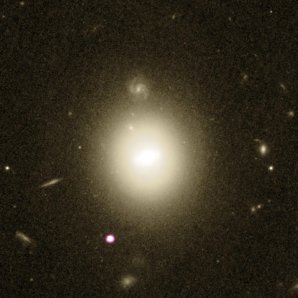 Bílo-fialovou barvou je znázorněna poloha rentgenového zdroje na periferii čočkovité galaxie uprostřed snímku Autor: X-ray – NASA/CXC/UNH/D. Lin et al; optical – NASA/ESA/STScI