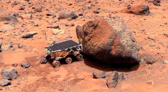 Malý rover Sojourner, který byl součástí mise Mars Pathfinder, zkoumá kámen neformálně pojmenovaný Yogi pomocí alfa-protonového rentgenového spektrometru. Autor: NASA