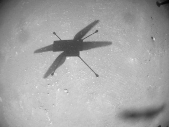 Stín helikoptéry Ingenuity pořízený navigační kamerou během jejího 19. letu na povrchu Marsu (na Zemi 8. února 2022, na Marsu 345. den od přistání Perseverance). Poblíž stínu je vidět i slabé sopy kol Perseverance, která tudy projela několik měsíců nazpět. Vrtulník se vrací do místa přistání roveru. Autor: NASA/JPL-Caltech