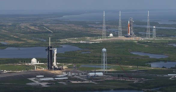Raketa Falcon 9 připravená s lodí Crew Dragon na misi Axiom 1 v popředí na floridské rampě LC-39A a superraketa SLS před testem tankování paliva při přípravách mise Artemis I na rampě LC-39B. Autor: NASA/Jamie Peer