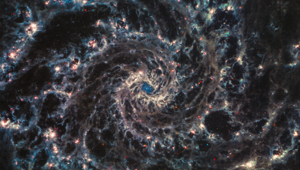 Galaxie M74 v podání přístroje MIRI dalekohledu Jamese Webba. Použité filtry: červená barva: MIRI F2100W, oranžová: MIRI F1130W, azurová: MIRI F770W, extra jasový kanál v šedé: MIRI F1000W. Autor: NASA/ESA/CSA/Judy Schmidt