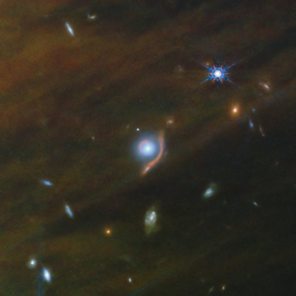Gravitační čočka, kdy jedna trochu bližší galaxie ohýbá světlo jiné vzdálenější se objevila v pozadí snímku IC 348 z JSWT Autor: ESA/Webb, NASA, CSA, K. Luhman, C. Alves De Oliveira, M. Zamani (ESA/Webb)